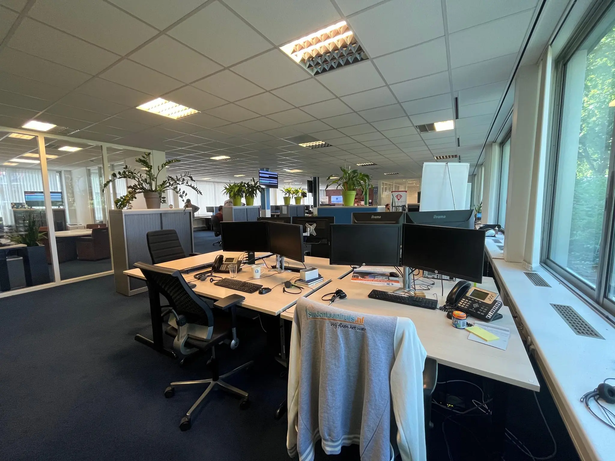 Modern kantoorinterieur aan de Jan van Eycklaan met meerdere werkplekken, computerschermen en grote ramen.